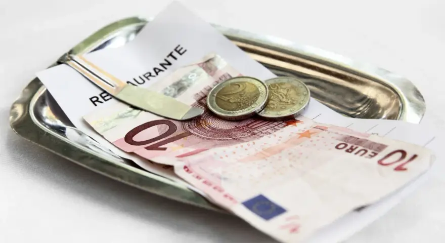 Na tacy leżą rachunek, banknot 10 euro i dwie monety. Tak wyglądają napiwki w Holandii.