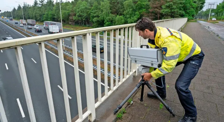 Policjant w Holandii ustawia radar na moście, by egzekwować przepisy drogowe.