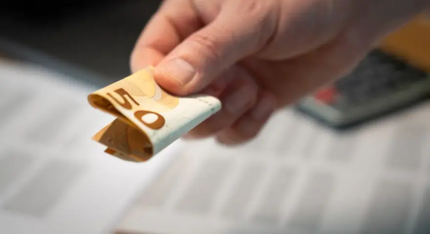 Dłoń trzyma złożoną pięćdziesięcioeuro banknot. Może to być zwrot zorgtoeslag.