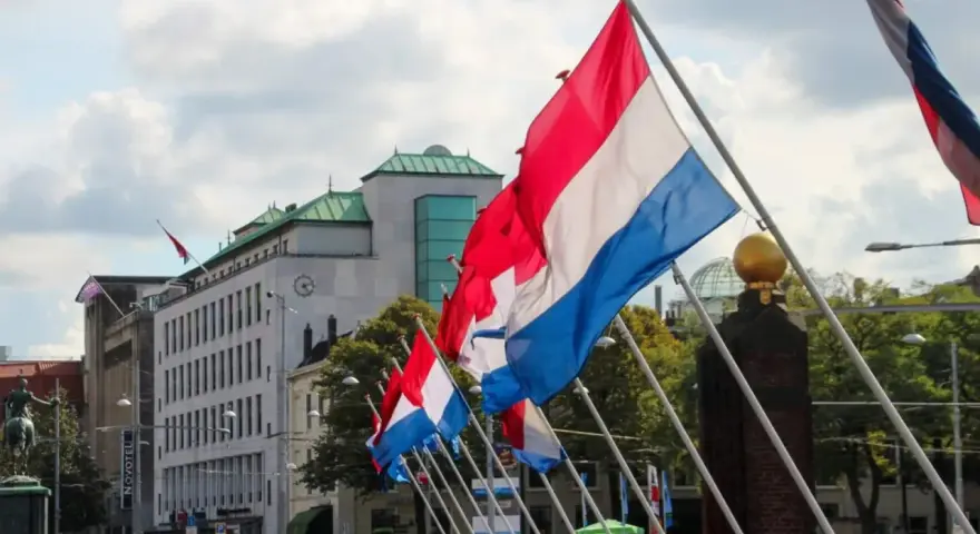 Holandia świętuje! Rząd flag narodowych powiewa na wietrze przed nowoczesnym budynkiem.