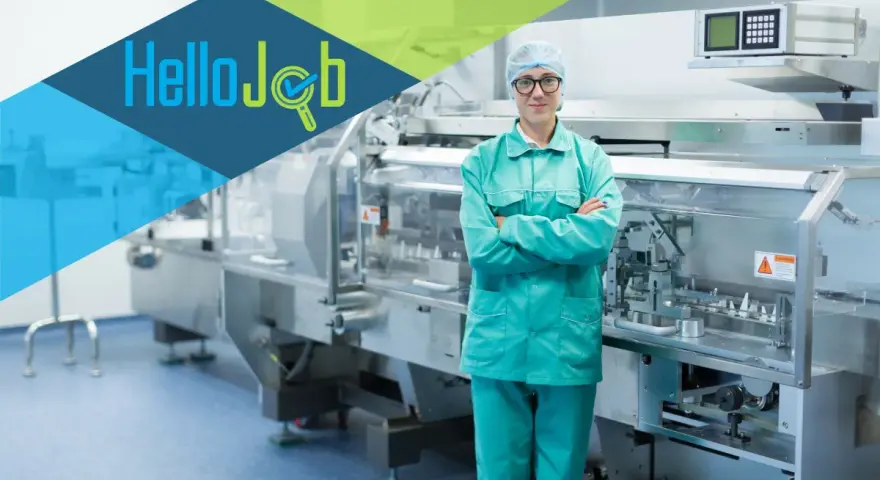 Pracownik w czepku i zielonym uniformie stoi przed linią produkcyjną. Szukasz pracy? Sprawdź cervo oferty pracy!