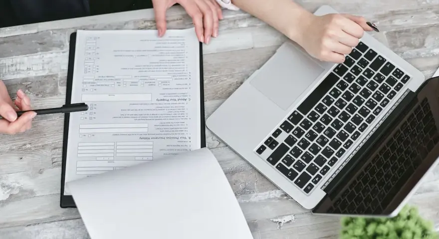 Dwie osoby przy biurku analizują dokumenty i laptopa. Planują swoją **pracę w Holandii**.