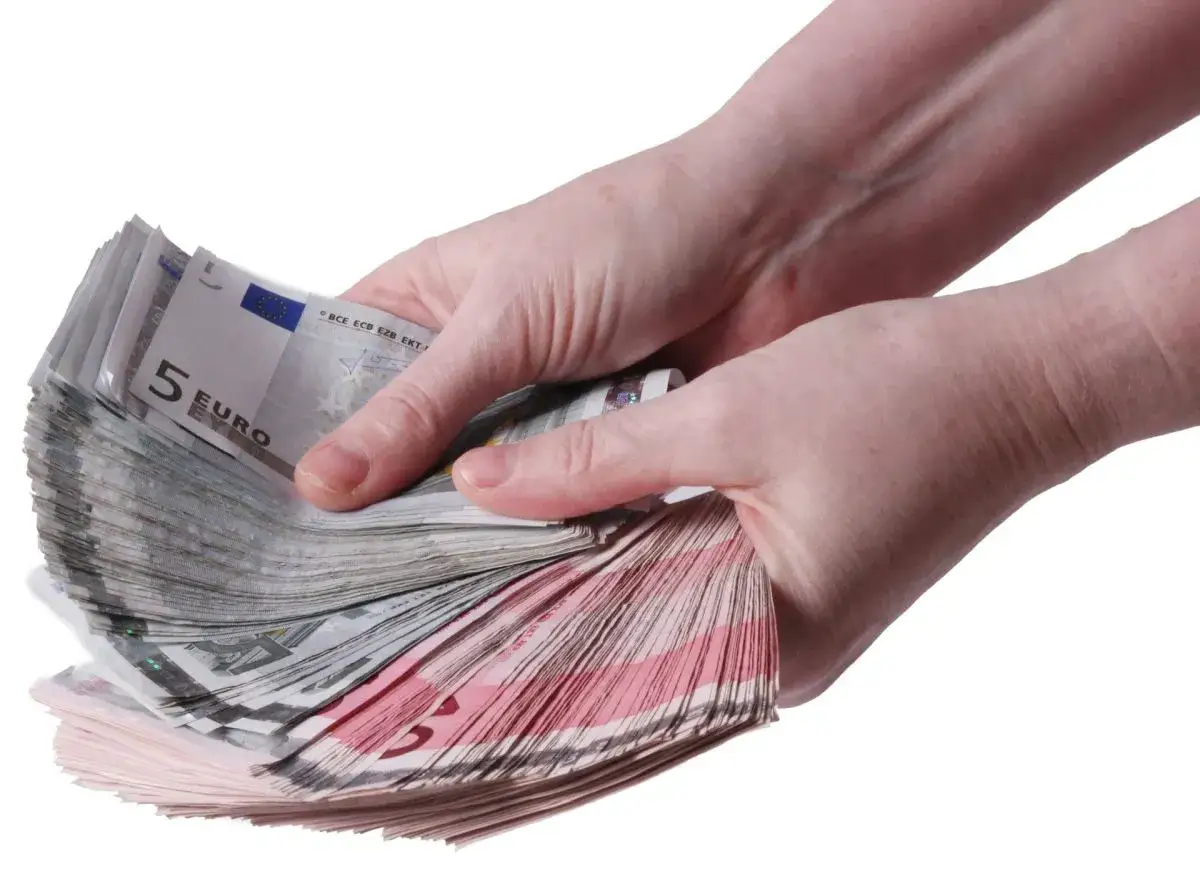 Dwie dłonie trzymające plik banknotów euro. Dowiedz się, jak wypłacić pieniądze ze stipp.