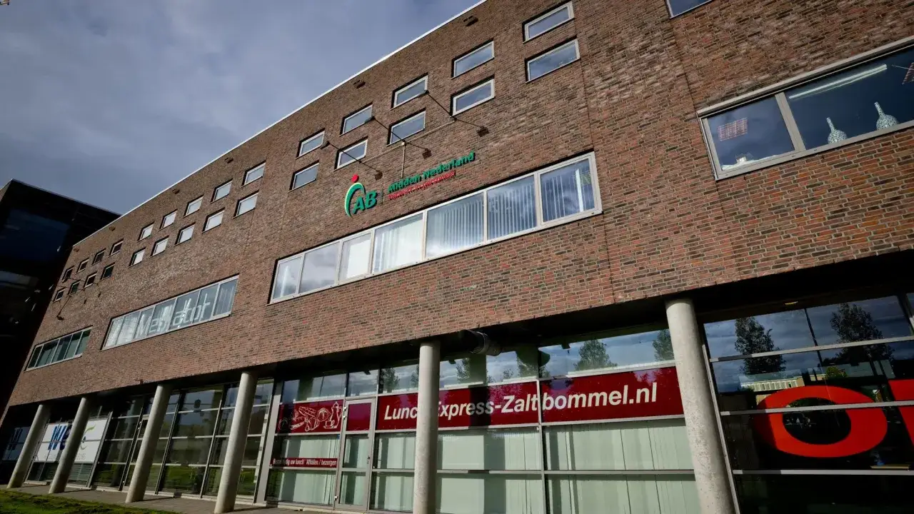Nowoczesny budynek z cegły z logo AB Midden Nederland. Na parterze szyld
