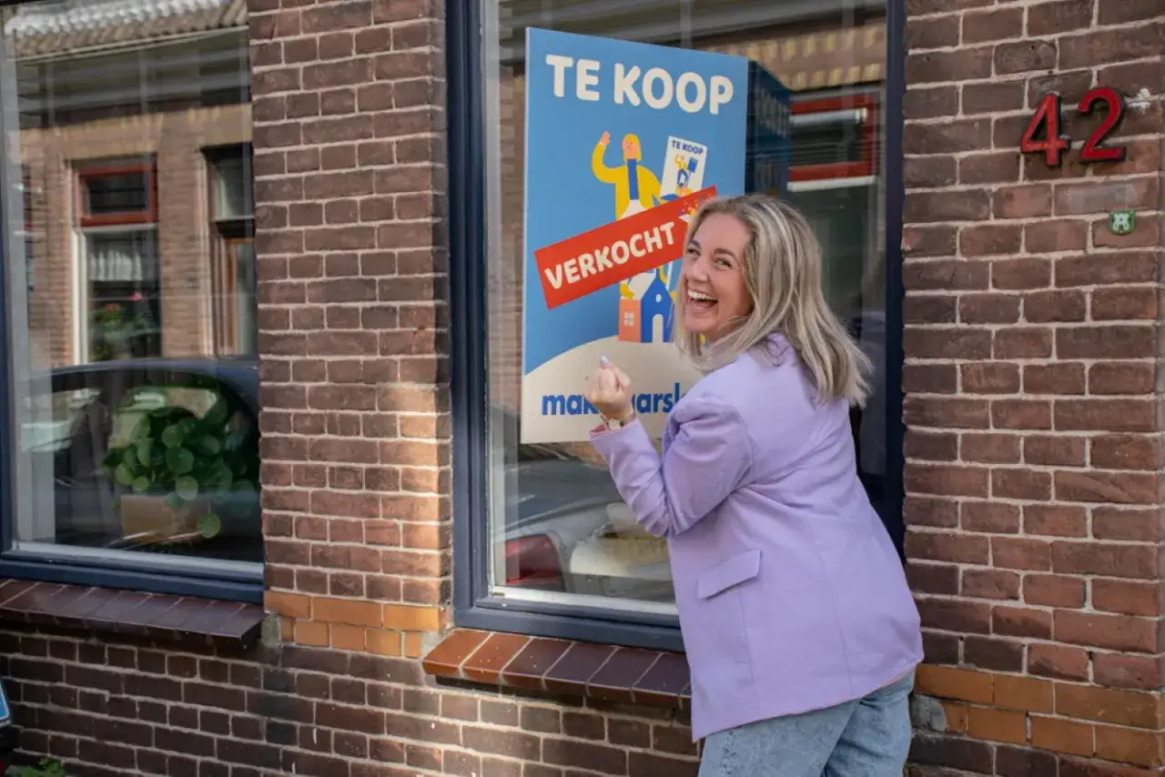 Szczęśliwa kobieta w fioletowej marynarce przy oknie z plakatem