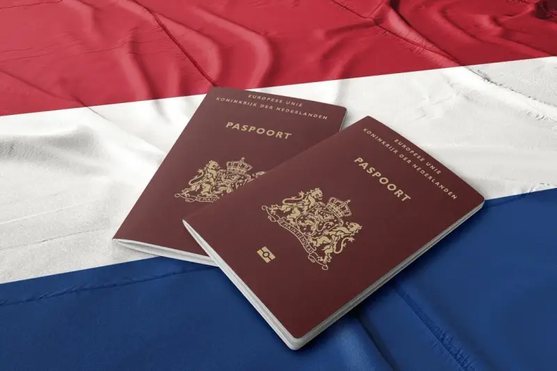 Dwa holenderskie paszporty na tle flagi Holandii. Dokumenty te mogą być kluczem do nowego życia dla wielu Polaków.