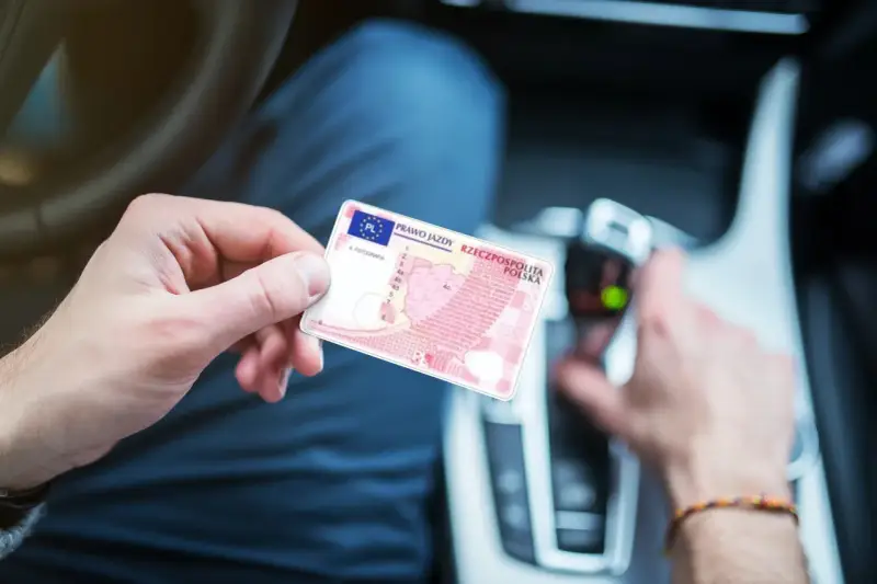 Polak trzyma polskie prawo jazdy w samochodzie. Dokument jest ważny w całej Unii Europejskiej, w tym w Holandii.